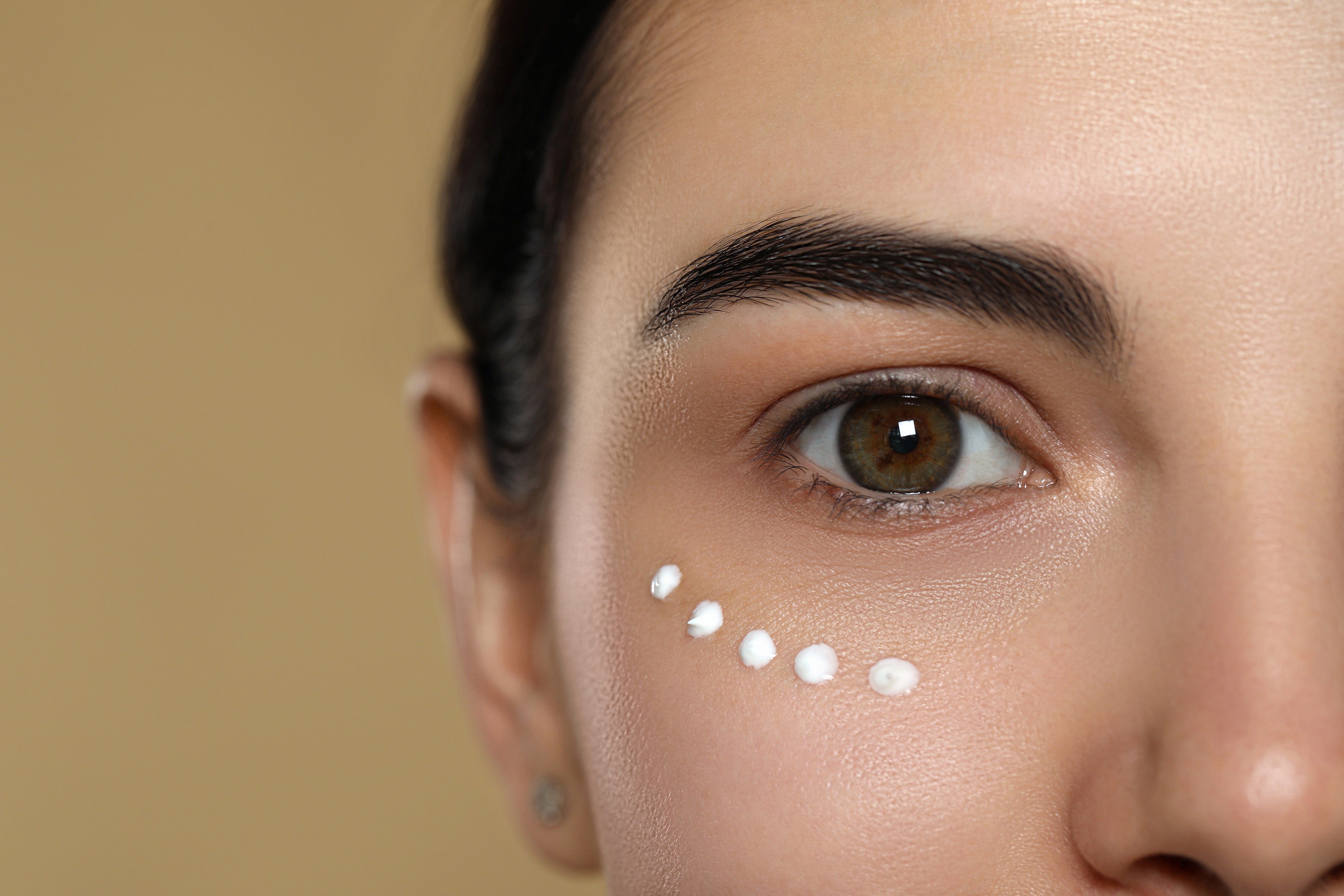young-woman-with-cream-skin-eye-against-beige-background-closeup.jpg